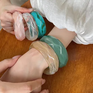 Detailed macro view of colorful acrylic chunky bangles with marbled texture on model's wrist