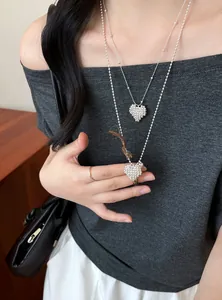 Detail view of elegant silver beaded heart pendant necklace styled with a gray outfit