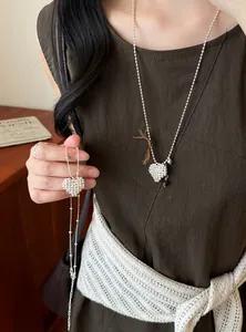 Detailed view of a stylish silver beaded heart necklace worn as a long sweater chain
