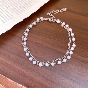 Macro detail of the double-layer silver chain bracelet decorated with elegant white pearls