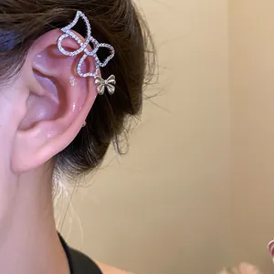 Primo piano di un ear cuff a farfalla in zircone con ciondolo a fiocco sull'orecchio