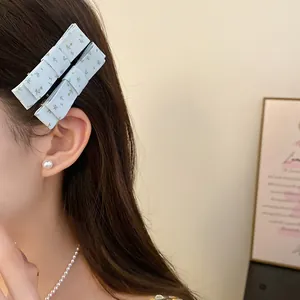 Detail view of elegant light blue floral fabric bow hair clips worn on side hair.