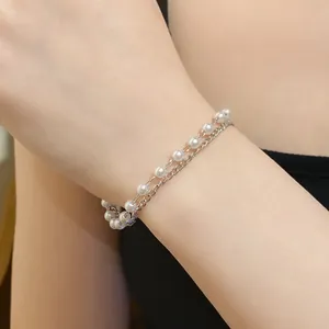 Detail close-up of a double-layered bracelet featuring white pearls and a silver metal chain