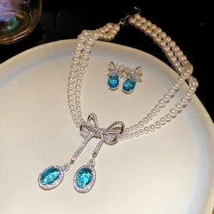 Détail du collier de perles élégant à double rang avec pendentif nœud en cristal bleu