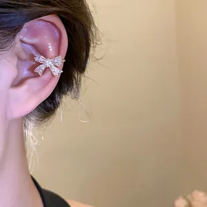 Dettaglio ravvicinato di un ear cuff a fiocco in zircone argento indossato sulla cartilagine.