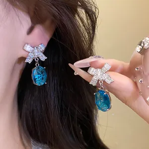 Gros plan de boucles d'oreilles nœud élégantes avec cristaux bleus et zircons