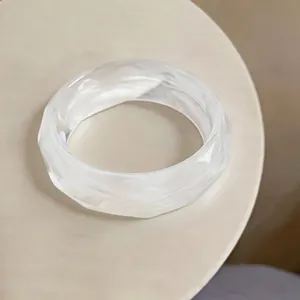 Detailed close-up of a white marbled acrylic bangle bracelet with faceted geometric design