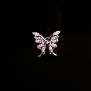 Vista macro di un earcuff a farfalla argentato con zirconi brillanti incastonati.
