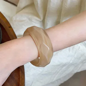 Close-up of a retro cream-marbled acrylic bangle with a chunky geometric design.