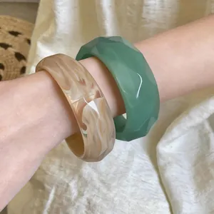 Macro view of retro chunky acrylic bangles with marble texture and faceted green jade look