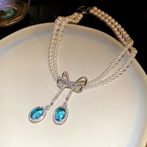Gros plan d'un collier de perles à deux rangs avec nœud et pierres bleues ovales