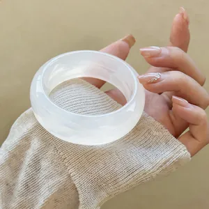 Close-up detail of a minimalist chunky white translucent acrylic bangle bracelet on wrist