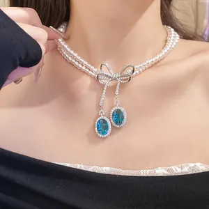 Vue détaillée du collier de perles double épaisseur avec pendentif nœud bleu
