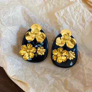 Detailed macro view of vintage black resin stud earrings with golden floral accents