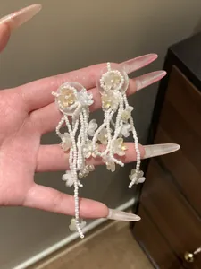 Close-up of handmade white and yellow beaded floral tassel earrings with long fringe