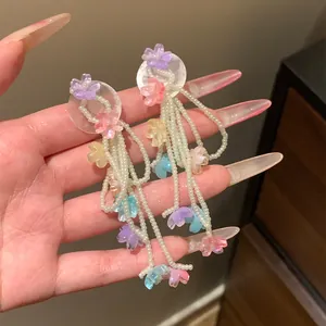 Detailed view of colorful floral earrings featuring white beaded tassels and clear base.