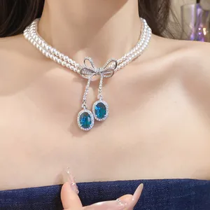 Élégant collier de perles à double rangée avec nœud en zircon et gouttes de cristal bleu.