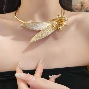Detailed macro view of a gold-toned metal flower and leaf necklace worn by a model