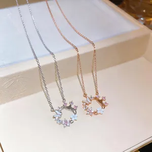 Close-up of zircon and shell flower butterfly circular pendant necklaces in silver and rose gold