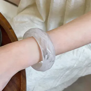 Detailed macro view of a translucent white marble pattern acrylic bangle on a woman's wrist