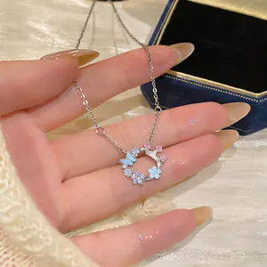 Detailed close-up of a silver zircon necklace featuring a butterfly and mother-of-pearl flowers