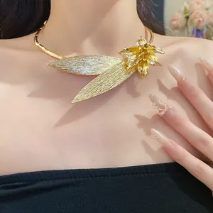 Detailed view of a large vintage gold metallic flower and leaf choker on a model's neck