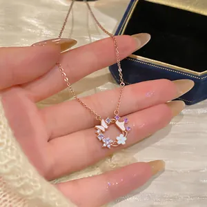 Detailed view of rose gold necklace with zircon butterfly and mother of pearl flower pendant