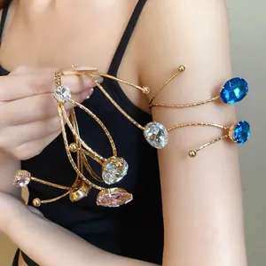 Elegant gold-tone metal arm cuff with oval blue and pink rhinestones on a model