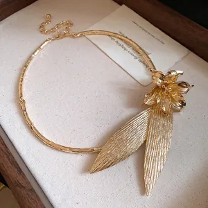Detailed macro view of vintage gold textured metallic flower and leaf necklace pendant