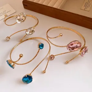 Elegant gold spiral arm cuff jewelry with oval crystal insets in multiple vibrant colors