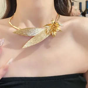 Detailed view of a vintage gold flower and leaf necklace worn on a collarbone