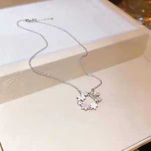 Detailed view of silver necklace with zircon flower and mother of pearl butterfly pendant.