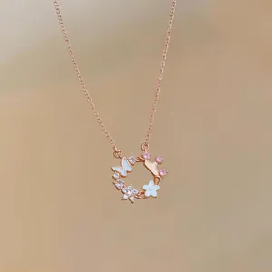 Close-up of rose gold necklace with zircon butterfly and mother of pearl flower pendant