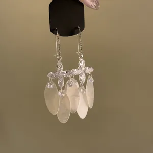 Detailed close-up view of silver flower earrings with sparkling zircons and shell tassels