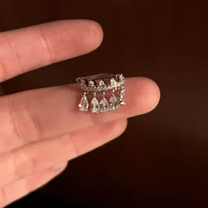 Close-up of a silver zircon pear-shaped ear cuff displayed on a finger for size reference