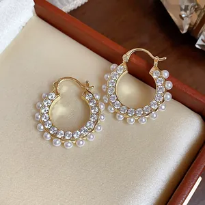 Nahaufnahme eleganter 14 Karat vergoldeter Creolen mit Zirkonia und Mini-Perlen
