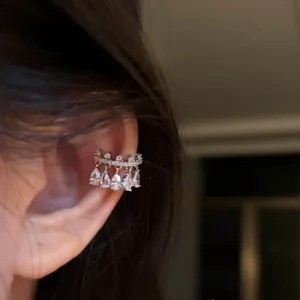 Close-up of elegant silver ear cuff with sparkling pear-shaped zircon drops