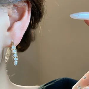Nahaufnahme von 14 Karat vergoldeten Perlen-Creolen mit Zirkonia am Ohr.
