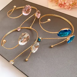 Detailed macro shot of gold spiral arm cuffs featuring elegant pink and blue oval crystals.