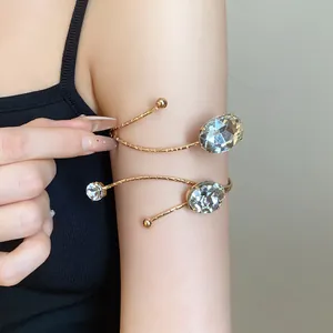 Detailed view of an elegant gold arm cuff with large oval rhinestones on a model's arm.