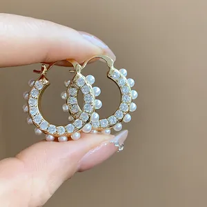 Detailansicht von 14k vergoldeten Creolen mit Zirkonia und eleganten weißen Perlen