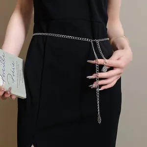 Close-up of minimalist silver chain waist belt with round pendant on a black dress
