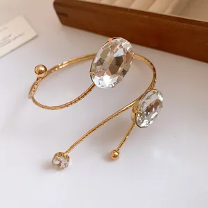 Detail view of a gold-toned metal arm cuff with oval and round faceted crystals