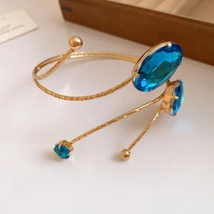 Detailed view of a gold arm cuff bracelet featuring faceted blue oval gemstones