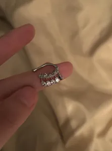 Close-up of a silver ear cuff with dangling pear-shaped cubic zirconia stones for non-pierced ears