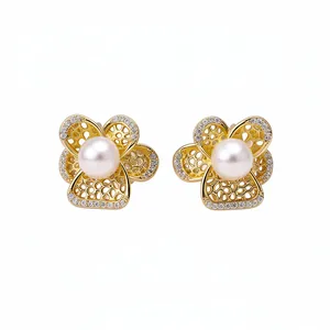 Elegante goldfarbene hohle Blumen-Ohrstecker mit weißen Perlen und Zirkon-Akzenten.