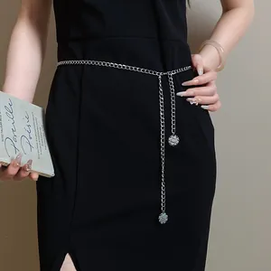 Elegant macro view of a silver chain waist belt with floral pendants on a black dress.