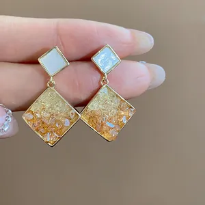 Nahaufnahme von 14 Karat vergoldeten Rauten-Ohrringen mit orangefarbenem Glas