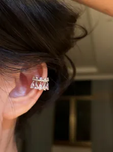 Detailed macro view of an elegant silver-toned zircon waterdrop ear cuff worn on the ear.