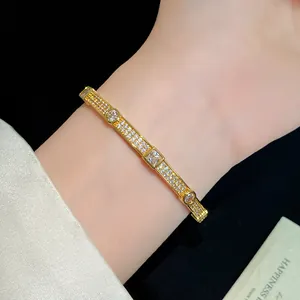 Detailed shot of an elegant 18K gold-plated zircon bangle worn on a lady's wrist.